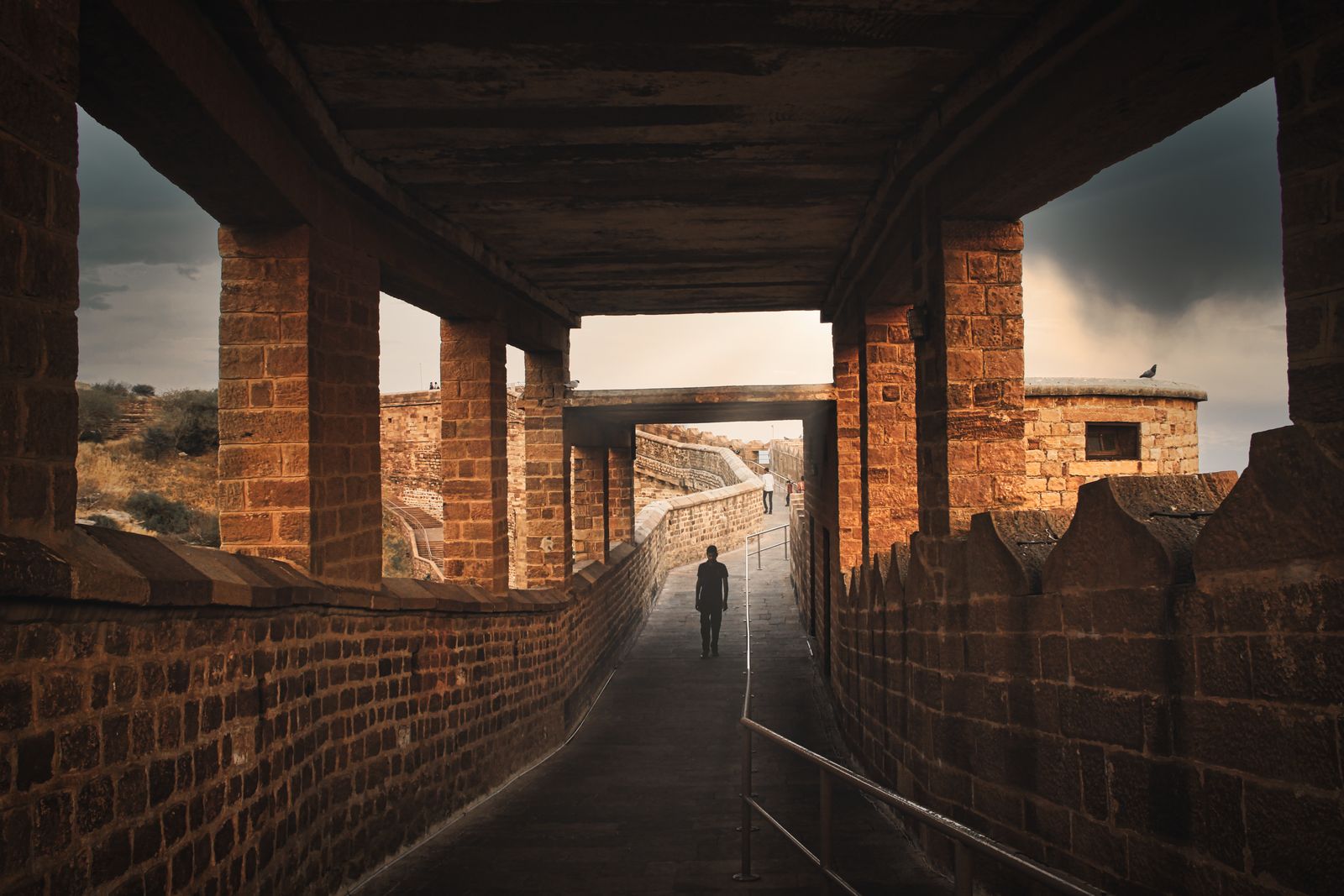 A visitor walking through a dramatic sandstone passage inside Mehrangarh Fort